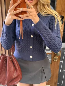 Close-up detail of navy blue cable-knit cardigan with vintage gold buttons on a model.