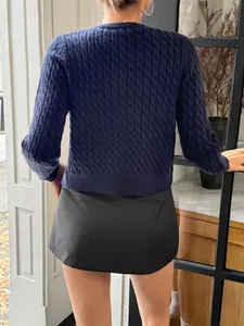 Detailed back view of a navy blue cable knit long sleeve sweater in a casual setting.