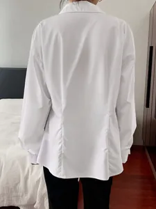 Detailed back view of a white long sleeve button-up shirt with elegant pleat detailing