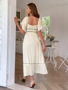 Back view of cream ruffle short-sleeved high waist holiday dress in a cozy kitchen setting