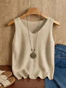 Elegante beige gebreide top met V-hals en een decoratief ketting-accessoire erbij.