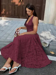 Model sitting outdoors wearing a burgundy deep V-neck jacquard dress for a vacation look