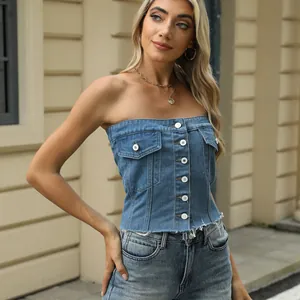 Dettaglio di un top a fascia in denim lavato blu con bottoni bianchi e orlo a frange alla moda