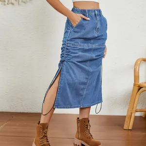 Detail of a washed blue denim midi skirt with side drawstring and slit design