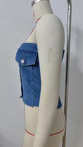 Vista laterale di un top a fascia in denim blu con bottoni frontali e orlo a taglio vivo