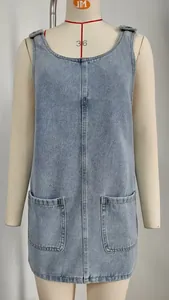 Macro detail of light blue washed denim pinafore dress featuring dual front patch pockets