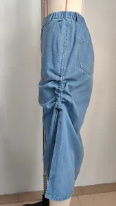Side detail of washed denim midi skirt with adjustable side drawstrings