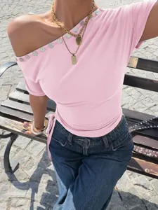 Detail eines pinken One-Shoulder-T-Shirts mit dekorativen Knöpfen und Seitenschleife