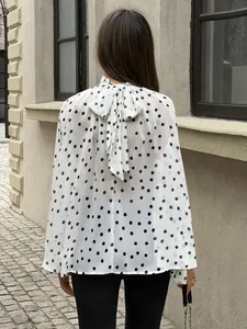 Back view of an elegant white polka dot blouse featuring a large decorative bow tie detail.
