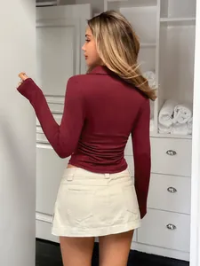 Rear view of an elegant burgundy long sleeve fitted shirt paired with a beige mini skirt