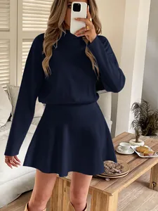 Detailed view of the navy blue long-sleeved knitted mini dress in a cozy interior setting.