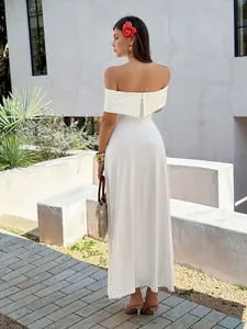 Back view detail of an elegant white off-the-shoulder maxi dress in a resort setting