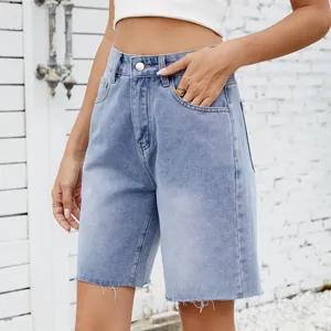 Close-up of washed denim shorts featuring pockets and raw edge frayed hemline