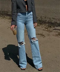 Detail of light blue ripped wide-leg jeans with distressed knee cutouts