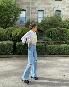 Model wearing light blue high-waisted ripped wide-leg denim jeans in an outdoor setting