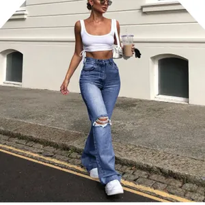Fashionable woman wearing high-waisted ripped blue wide-leg jeans in a street photo