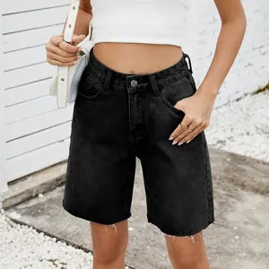 Detail of high-waist washed black denim shorts with raw hem and straight fit