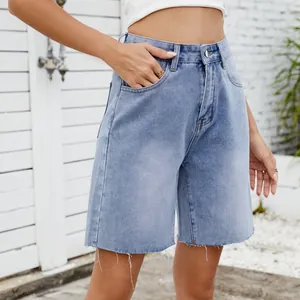 Detailed shot of light wash denim shorts featuring a raw frayed hem and classic stitching.