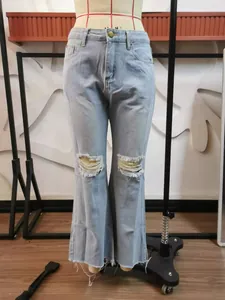 Detailed view of light blue ripped flare jeans with distressed knees and frayed hems.