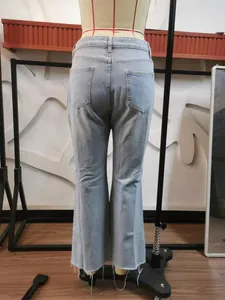 Detailed back view of light blue denim flare jeans featuring raw hem and back pockets