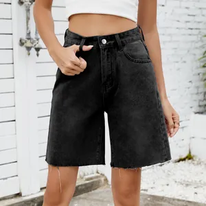 Detailed close-up showing the texture of washed black denim shorts with stylish frayed hem