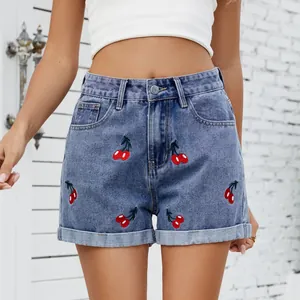 Gedetailleerde weergave van kersenborduurwerk op gewassen denim shorts met hoge taille.
