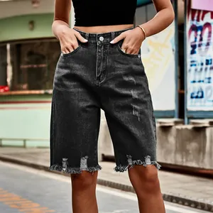 Macro view of women's black distressed denim shorts featuring raw frayed hem details