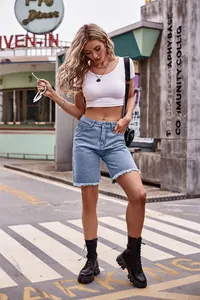 Modella elegante che presenta bermuda di jeans azzurri con orlo a vivo all'aperto