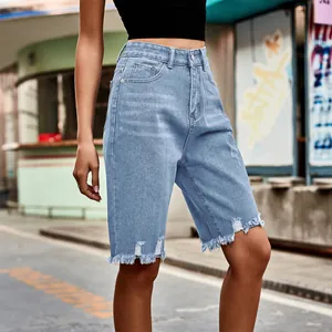 Close-up of high-waisted denim bermuda shorts with distressed details and frayed hem