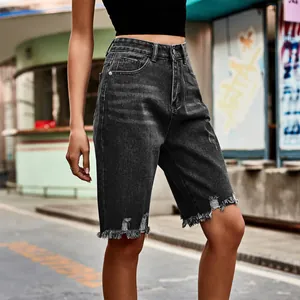 Close-up of charcoal grey distressed denim bermuda shorts featuring frayed fringe hems.