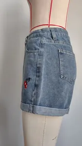 Zijaanzicht detail van lichtblauwe denim shorts met een rood kersen borduurontwerp.