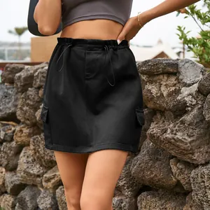 Outdoor detail view of a black denim cargo mini skirt featuring a drawstring waist