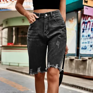 Detailed view of high-waisted distressed black denim shorts with raw hem and fringe