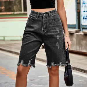 Detail view of high-waisted dark grey distressed denim shorts with frayed tassels.