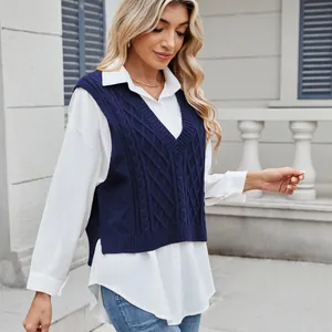 Close-up of navy blue V-neck cable knit sweater vest layered over a white long-sleeve shirt