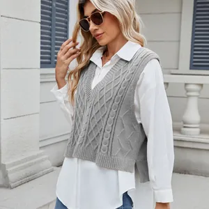 Detail of a gray cable-knit V-neck sweater vest layered over a white long-sleeve shirt