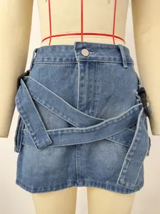 Close-up detail of blue washed denim mini skirt featuring decorative straps and cargo pockets