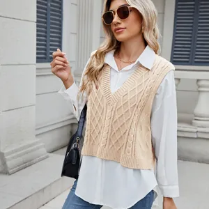 Detail view of a beige cable-knit V-neck vest styled with a white shirt and jeans