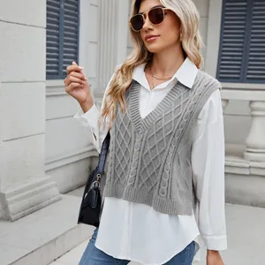 Close-up detail of a grey cable-knit V-neck sweater vest layered over a white shirt.
