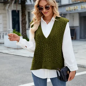 Street style view of a woman wearing a green V-neck cable-knit sleeveless sweater vest.
