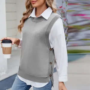 Detail of women's grey knitted vest with side buttons and slit over a white shirt.