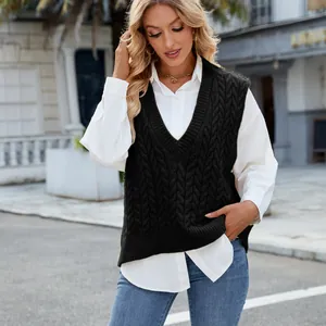 Detail of black V-neck cable knit sweater vest styled with white shirt and jeans