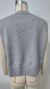 Back view of a loose grey knitted sweater vest with detailed ribbed hem texture.
