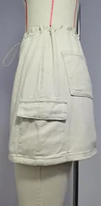 Detailed close-up of a beige denim cargo skirt featuring a large side pocket and flap