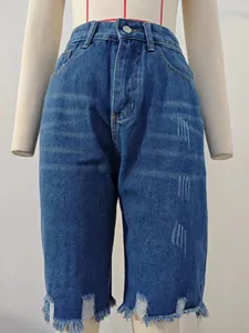 Detailed view of distressed denim shorts with frayed fringed hem and cat whisking