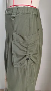 Detail view of the drawstring cargo pocket on an olive green midi skirt