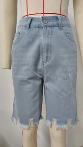 Detailed view of light blue high-waisted distressed denim shorts with frayed hem