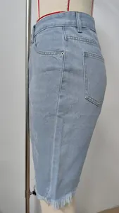 Detail of light blue ripped denim shorts featuring a raw frayed fringe hem decoration.