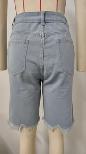 Detail view of light blue denim shorts featuring frayed tassel hems and back pockets