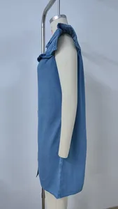 Side profile of a blue washed denim sleeveless dress featuring ruffled shoulder details